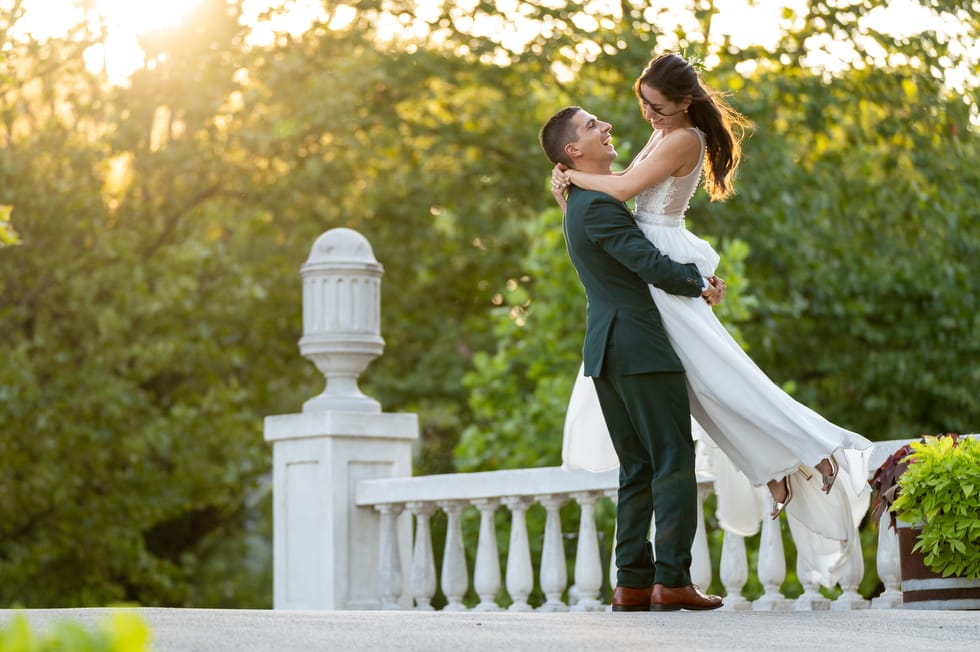 Esküvői kreatív fotózás közben a férj felemeli a menyasszonyt a balatonalmádi sétányon a Balaton mellett