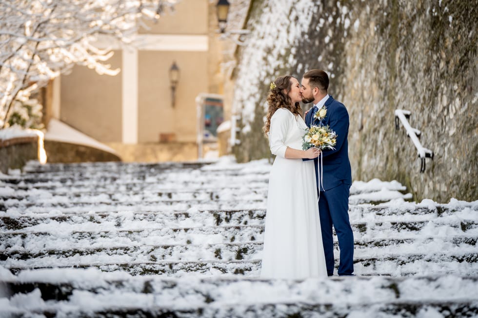 Friss házaspár esküvői kreatív fotózás közben télen a veszprémi vár havas lépcsőjén