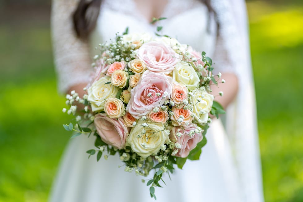 Gyönyörű esküvői csokor a menyasszony kezében kreatív fotózás közben