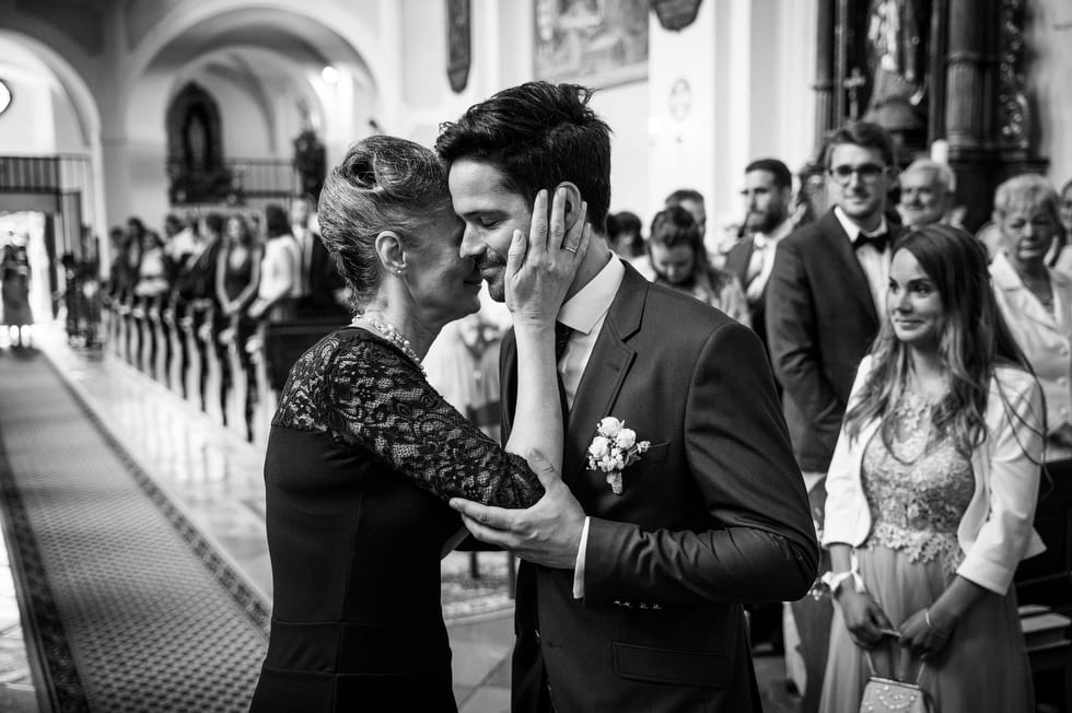 Édesanya megöleli a fiát az esküvője napján a templomi szertartás előtt, miután bekísérte a templomba