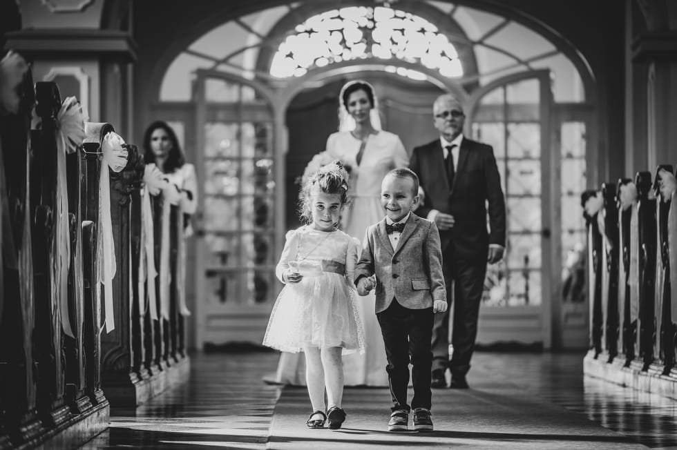 Gyerekek bevonulnak a feleség előtt a templomi szertartás alatt és rózsaszirmot szórnak.